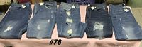 Five pairs of blue distressed Wax Jeans laid flat showing front, varying washes