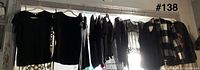 Nine black tops hanging on hangers