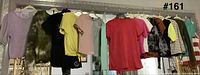 Row of twelve assorted women’s short-sleeve tops hanging on rack