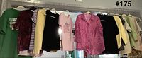 Nine assorted tops and sweaters hanging on rack