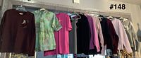 Row of nine women’s tops and sweaters on hangers
