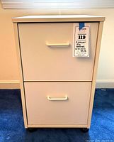 Front view of white two-drawer file cabinet showing handles and overall condition