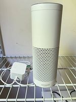 Front view of Amazon Echo speaker with power adapter