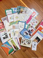 Wide view of mixed stack of greeting cards spread on wood floor