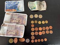 Overall view: four banknotes, assorted euro coins, souvenir tokens displayed on black surface