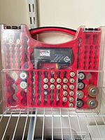 Front view of red battery organizer showing tester and assorted batteries