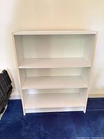Front view of white laminate bookcase showing three shelves