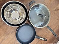 Top view of all items: frying pan, deep sauté pan with lid, nested mixing bowls