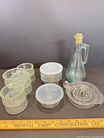 Group shot of all glass items including bowls with lids, ramekins, juicer and cruet