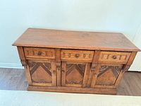 Front view of sideboard showing three drawers and three carved doors
