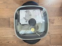 Top view of skillet with glass lid, manual and temperature probe inside