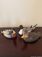 Three carved wooden duck decoys on table