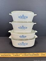 stack of four CorningWare Cornflower dishes with lids showing graduated sizes and pattern