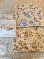 Blue and brown-tan floral placemats alongside packaged white napkins