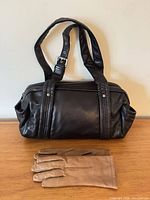 Front view of black leather handbag with tan gloves