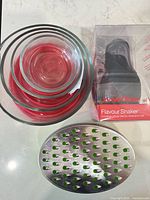 Stacked glass bowls with red lids, boxed Jamie Oliver Flavour Shaker, stainless-steel cheese grater