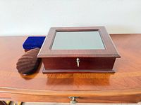 Mahogany jewelry box with glass top, blue velvet case, brown velvet pouch on table