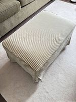 Ottoman angled view showing striped fabric and skirt