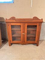 Front view of oak hutch topper showing glass doors and carved crest