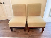 Front view of both beige armless dining chairs