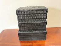 Three black wicker baskets stacked showing size uniformity and color