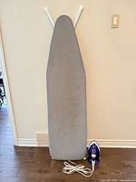 Ironing board front view standing upright beside iron