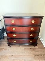 Front view of bow-front cherry-mahogany dresser with brass oval pulls
