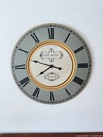 Front view of round vintage-style wall clock showing dial, numerals and centre design