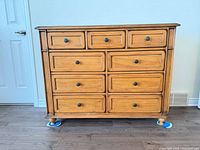Front view showing nine drawers, knobs, honey finish