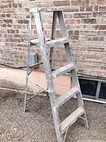 Full view of 4-step aluminum A-frame ladder with paint splatters