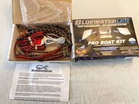 Closed box showing BlueWaterLED Pro Boat Kit graphics beside opened box revealing LED strips, controller, wiring and instructions