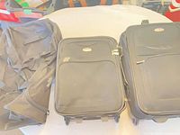 Two rolling suitcases and folded duffel on table