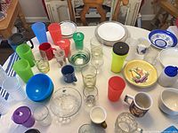 Mixed tumblers, bowls, plates and mugs arranged on table