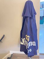 Folded navy patio umbrella showing Corona Extra logo