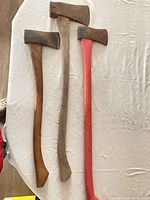 Three axes laid side by side for full view of handles and heads