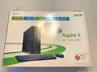 Front of Acer Aspire X retail box showing model AXC-704G-EW51 and illustration of tower, keyboard, mouse