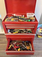 Full view of red toolbox with drawers open showing assorted tools