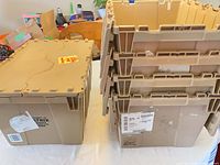 Five tan plastic crates, four stacked showing side profile, one upright with lid closed