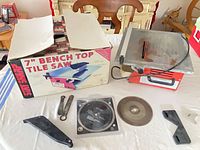 Lot overview showing saw, box, blades, wrenches and guards