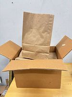 Cardboard shipping box with brown paper bags inside