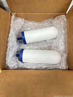 Two white ceramic filter candles with blue ends in bubble wrap inside box