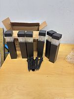 Six black rectangular solar lights standing upright with stakes laid out in front
