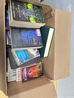 Open box showing multiple books including Wicked Resurrection on top