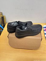 Pair of black slip-on loafers on top of box, side view