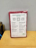Front of sealed package displaying instruction sheet and red curtain material
