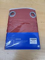 Front view of sealed package showing burgundy curtain panels with grommets