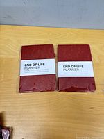 Two red End Of Life Planners in plastic wrap on table