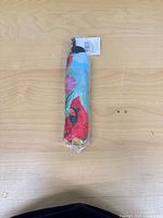 Folded umbrella in sealed plastic showing cardinal graphic