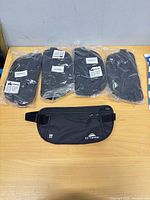 five EZ Traveler money belts on table, four sealed one loose