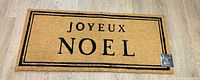 Full view of doormat showing JOYEUX NOEL text and tag attached